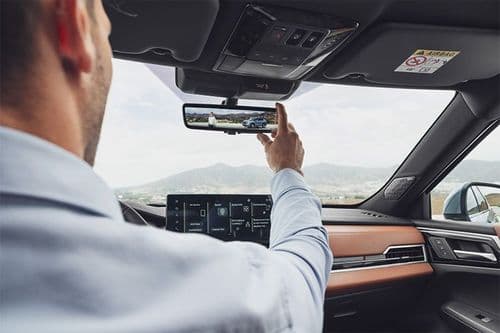 Man with a shirt aligns rear-view mirror in Mitsubishi interior