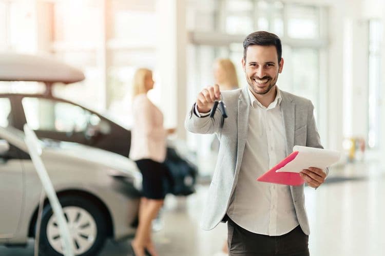A car salesman hands over a key