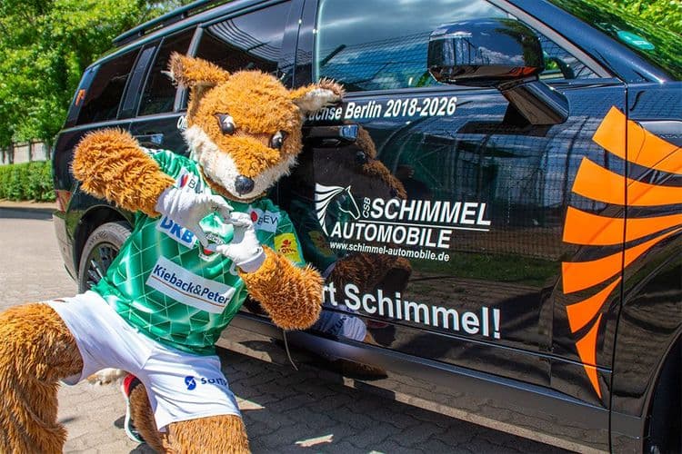 Fuchsi, la mascota de la Füchse Berlin, delante de un Hyundai SANTA FE negro.