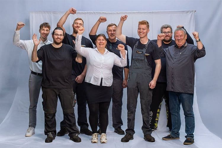 team junger menschen vertrieb und service vor grauem hintergrund lachen und heben haende in die luft