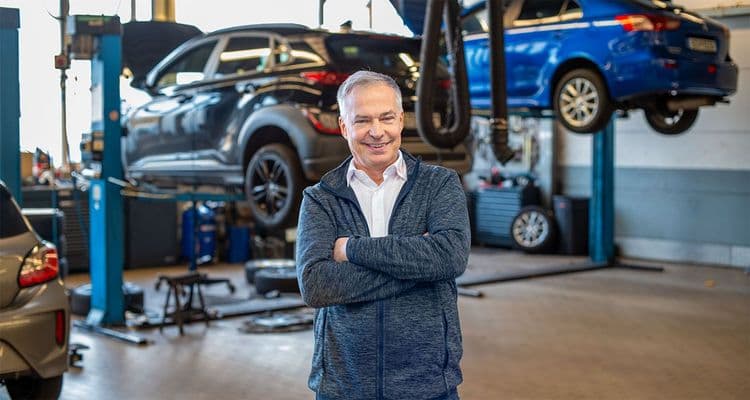 Руководитель сервисной службы в мастерской перед автомобилями