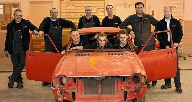 Workshop team in front of classic car