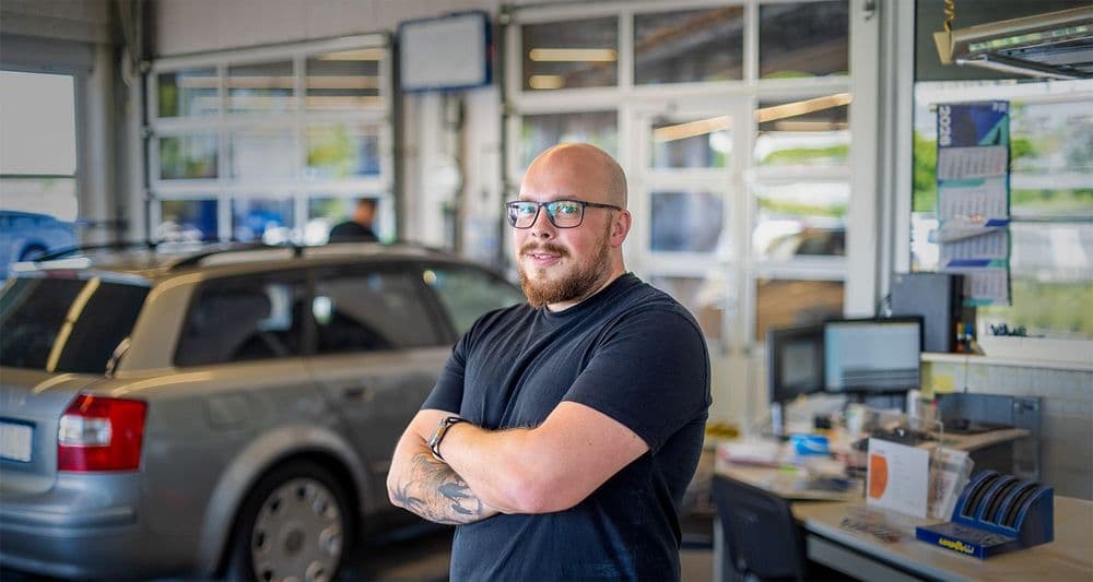 Karriere Serviceberater vor silbernem Auto in der Dialogannahme